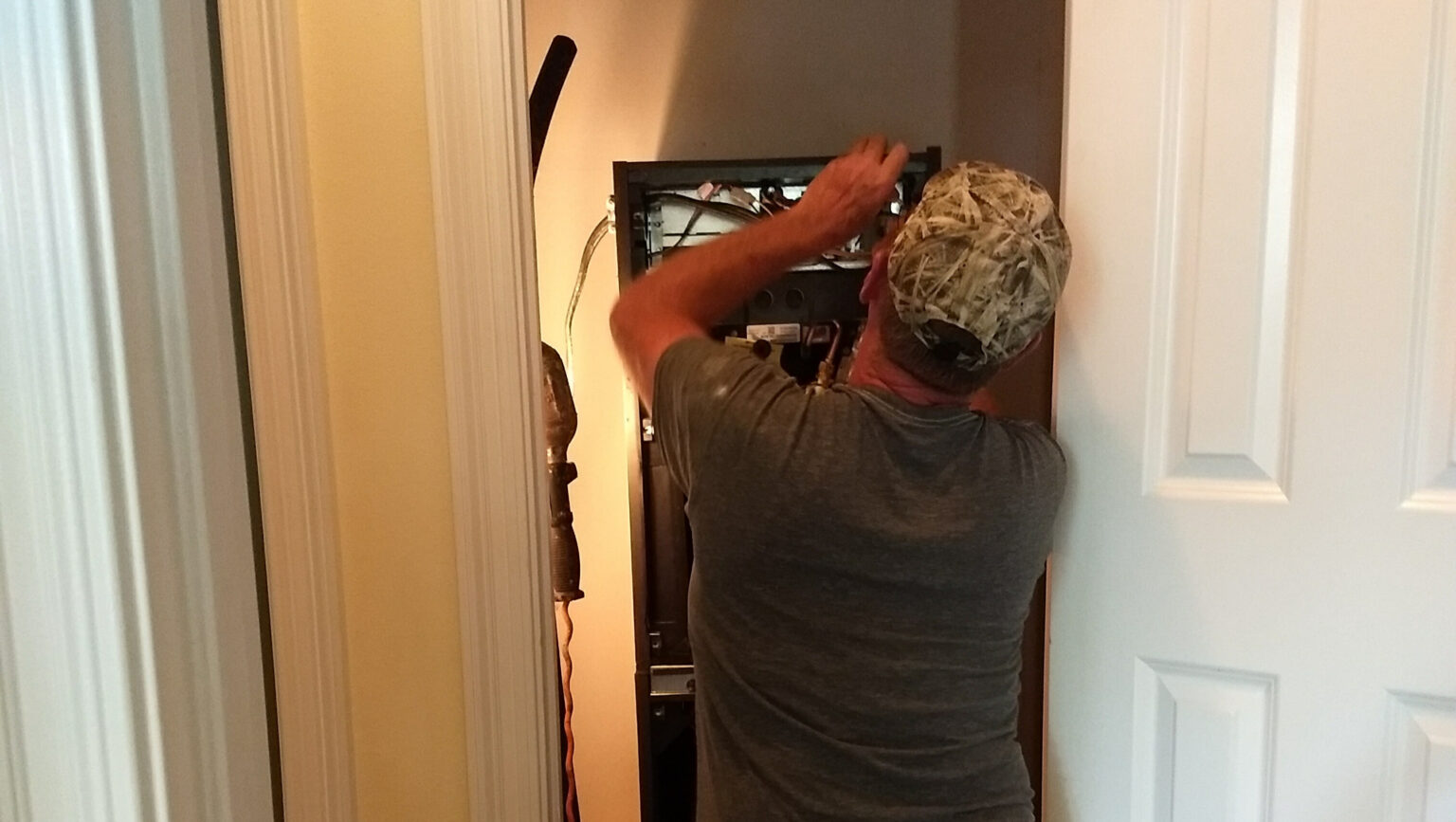 Technician working on indoor unit in closet/mechanical area